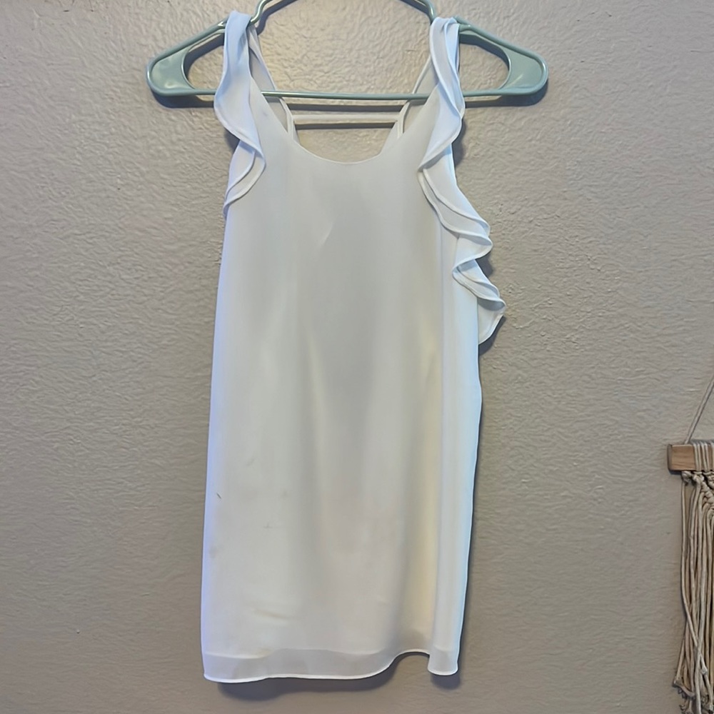 White dressy tanktop with ruffles on sleeves and has an open back. Size large